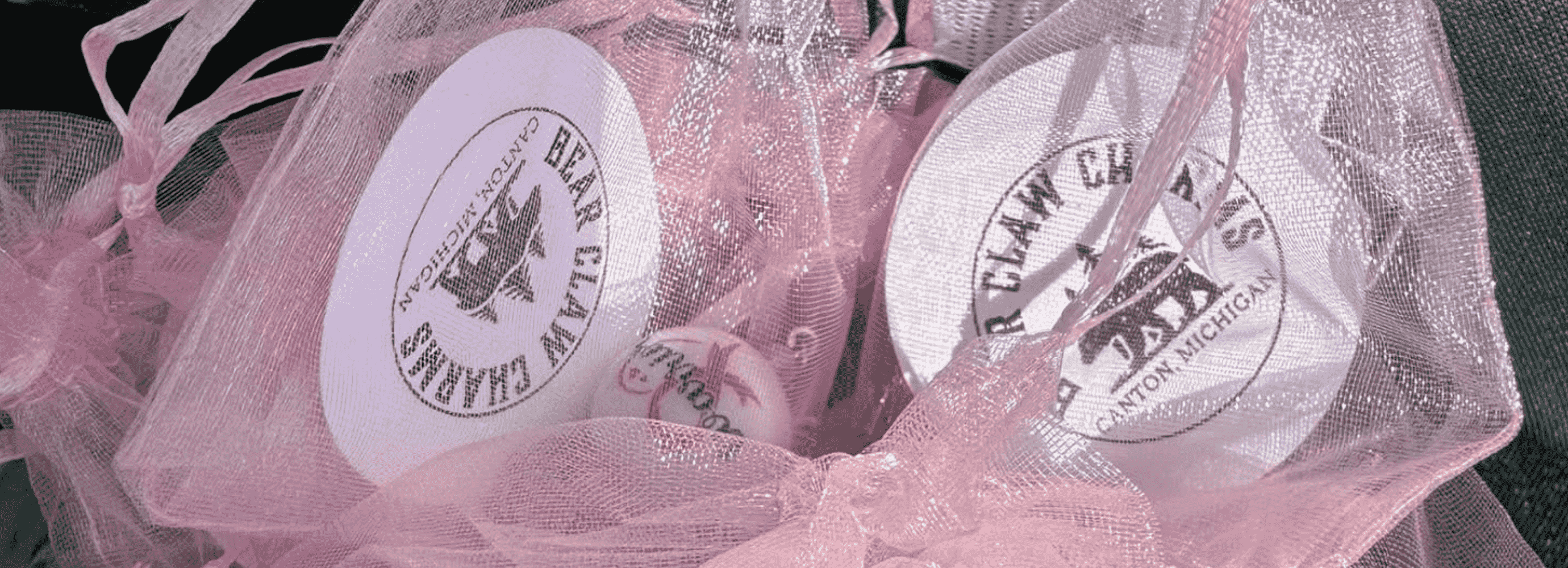 Multiple pink bags of breast cancer awareness charms.
