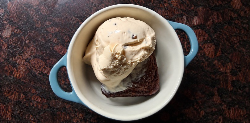 Ice cream and brownie in a small white and blue bowl. 