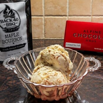 Ice cream in a bowl made with pretzels and fudge with a bag of pretzels and a box of fudge.