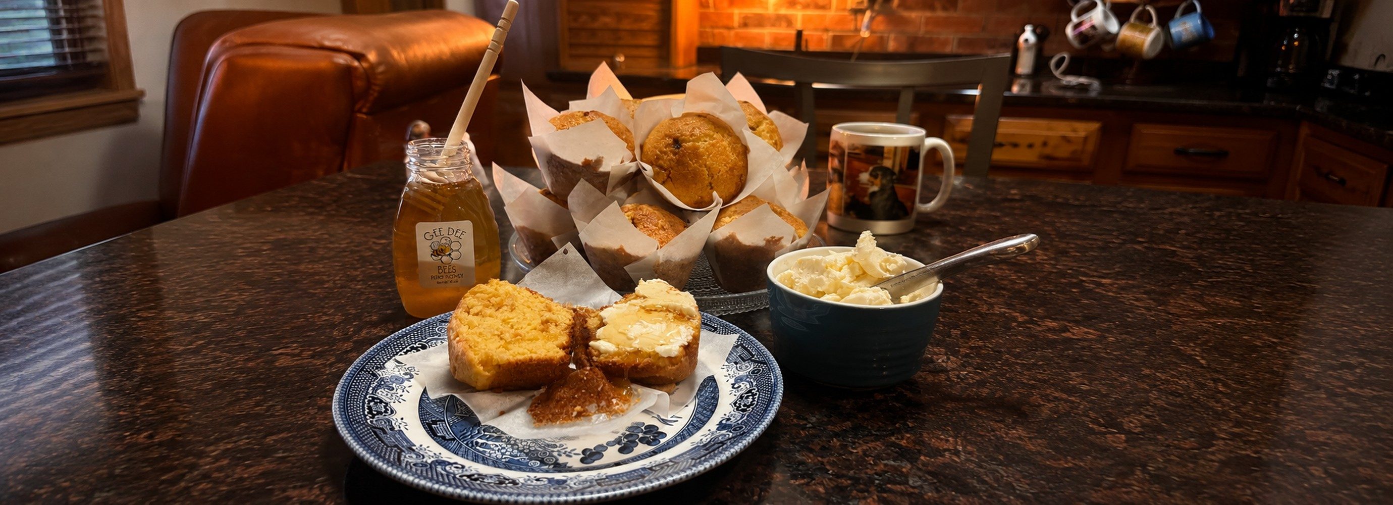 A table with corn bread muffins, butter, and honey.