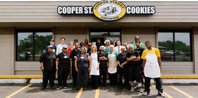 Group of people standing in front of a Cooper Street Cookies store. 
