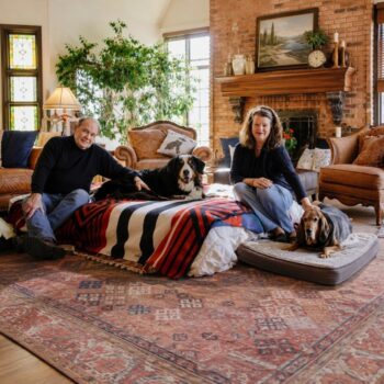 A man and a woman in a living room with two dogs.