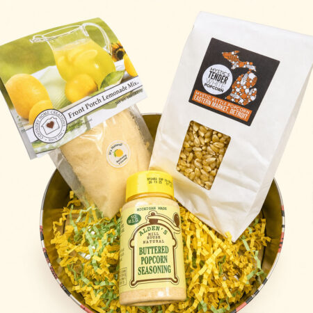 Tin filled with popcorn-related items such as seasoning, popcorn kernels, and lemonade mix.