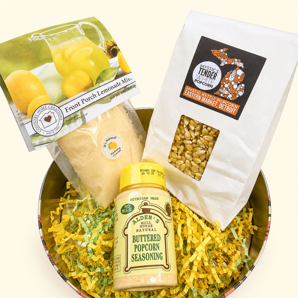 Tin filled with popcorn-related items such as seasoning, popcorn kernels, and lemonade mix.