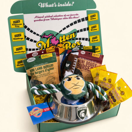 Gift box filled with MSU-themed gifts for dogs, including a dog bowl, toys, and snacks.
